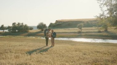 Güzel turistler nehir kenarında el ele tutuşurken öpüşürler.