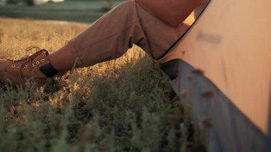 Doğada çadırda oturan bir kadının bacaklarının yakın görüntüsü.