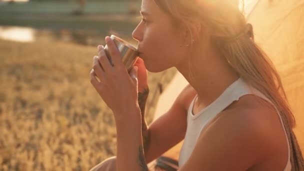 Widok Boku Pozytywnej Kobiety Pijącej Gorącą Herbatę Siedząc Namiocie — Wideo stockowe