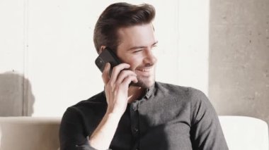 Gülümseyen işadamı telefonda konuşuyor ve eve bakıyor.