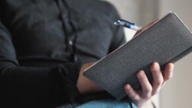 Gözlüklü gülümseyen yakışıklı iş adamının yakın plan görüntüsü not defterine bir şey yazıp evde yüksek sesle konuşurken.