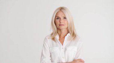 Olgun bir kadın beyaz stüdyodaki bir şeye katılıyor.