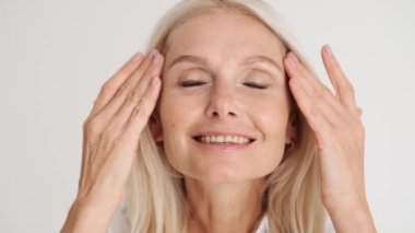 Mutlu, olgun bir kadının beyaz stüdyodaki görüntüsünü düzeltirken yakın plan görüntüsü.