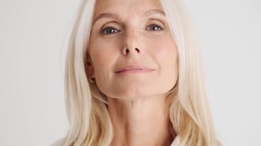 Yakışıklı olgun kadının beyaz stüdyodaki kameraya bakışını yakından çek.