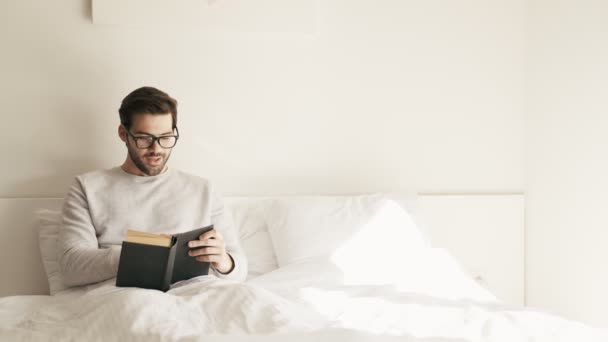 Hombre Concentrado Anteojos Leyendo Voz Alta Mientras Está Acostado Cama — Vídeos de Stock