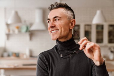 Yakışıklı mutlu adam gülümsüyor ve mutfağa bakıyor.