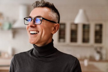 Gözlüklü yakışıklı mutlu adam gülümsüyor ve mutfağa bakıyor.