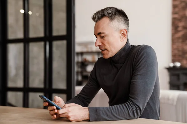 Handsome Focused Man Using Mobile Phone While Sitting Home — Stock Photo, Image