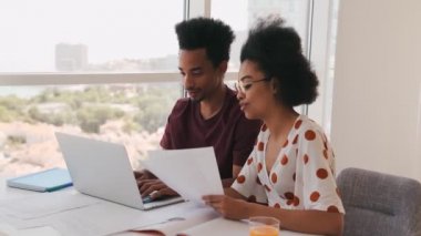 Gülümseyen Afrikalı kadın, bir kağıt parçasından dizüstü bilgisayarında daktilo yazan Afrikalı erkek arkadaşına kadar dikte ediyor.