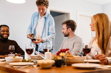 Memlekette şükran günü yemeğinde şarap içen çok ırklı mutlu arkadaşlar.