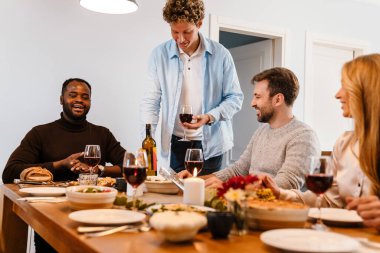 Memlekette şükran günü yemeğinde şarap içen çok ırklı mutlu arkadaşlar.