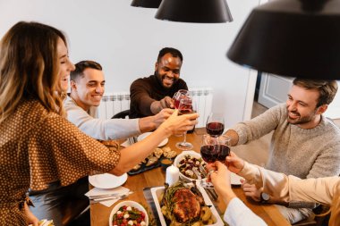 Memlekette şükran günü yemeğinde şarap içen çok ırklı mutlu arkadaşlar.