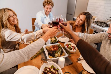 Memlekette şükran günü yemeğinde şarap içen çok ırklı mutlu arkadaşlar.