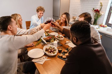 Memlekette şükran günü yemeğinde şarap içen çok ırklı mutlu arkadaşlar.
