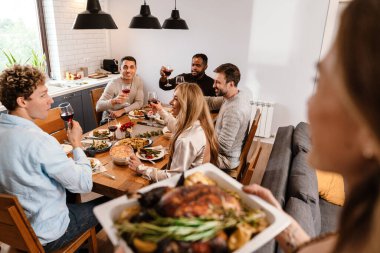 Memleketteki Şükran Günü yemeğinde hindi yiyen çok ırklı mutlu arkadaşlar.