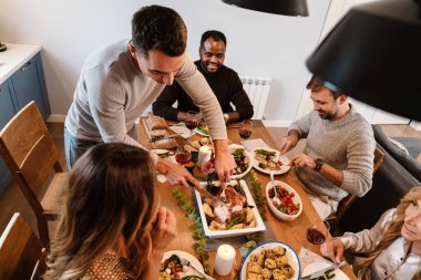 Memleketteki Şükran Günü yemeğinde hindi yiyen çok ırklı mutlu arkadaşlar.