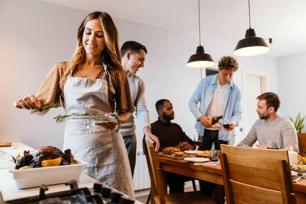 Beyaz çift Şükran Günü yemeği için evde arkadaşlarıyla hindi pişiriyor.