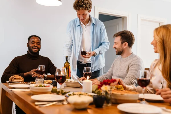 Memlekette şükran günü yemeğinde şarap içen çok ırklı mutlu arkadaşlar.