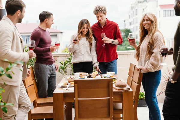 感謝祭のディナーの間にワインを飲む多人種の幸せな友人屋外 — ストック写真