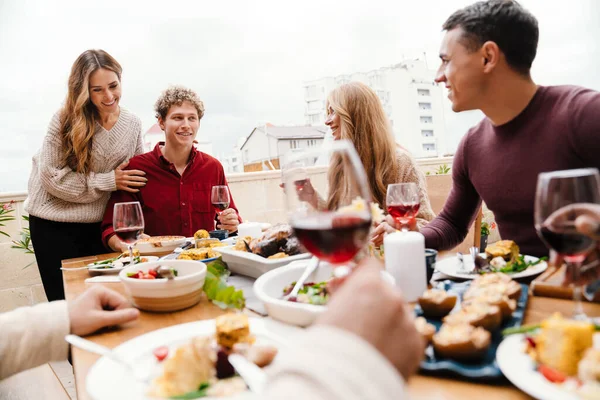 Multiracial happy friends drinking wine during thanksgiving dinner outdoors
