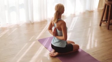 Arkasından el ele tutuşan ve yoga minderindeki pencereye bakan güzel bir kadın.