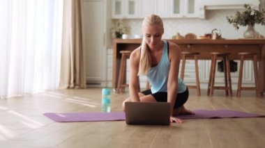Yoga minderinde çalışmadan önce laptopa bakan güzel bir kadın.