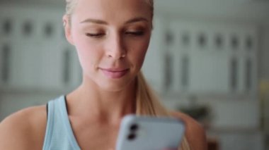Evde telefonla mesaj atan mutlu sarışının yakın plan görüntüsü.