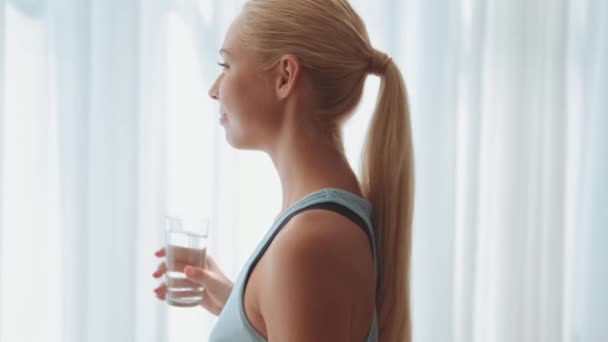 Positieve Vrouw Gaat Met Een Glas Water Een Raam Openen — Stockvideo