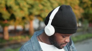 Kendine güvenen bir adamın kulaklık takıp sokakta müzik dinlediği yakın plan bir görüntü.