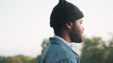 Kulaklıklı konsantre olmuş Afrikalı bir adam caddedeki manzaraya bakıyor.