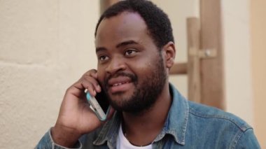 Kahvede telefonla konuşan gülümseyen Afrikalı adamın yakın çekim görüntüsü.