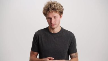 Beyaz stüdyoda kameraya bakan kıvırcık saçlı adamı gücendirdim.