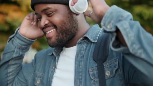 Sorrindo Homem Africano Ouvir Música Fones Ouvido Enquanto Caminha Rua — Vídeo de Stock