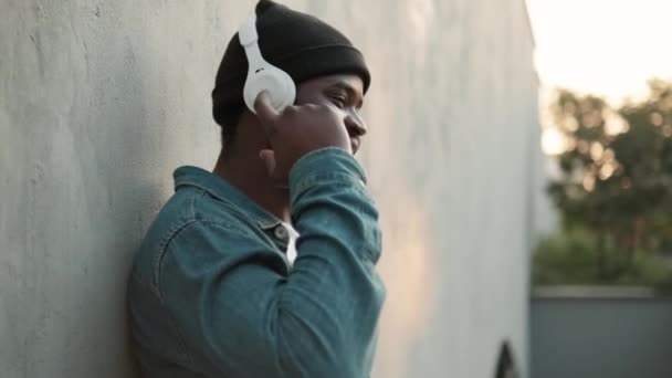 Positieve Afrikaanse Man Luistert Muziek Koptelefoon Buurt Van Betonnen Muur — Stockvideo