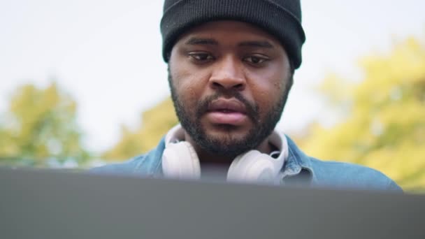 Vista Perto Homem Africano Fones Ouvido Digitando Laptop Parque — Vídeo de Stock