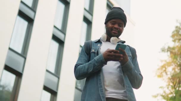 Kulaklıklı Olumlu Bir Adamın Sokakta Telefonla Mesajlaşması — Stok video