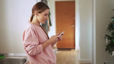 Evde telefonla bantla konuşan konsantre bir kadının yan görüntüsü.