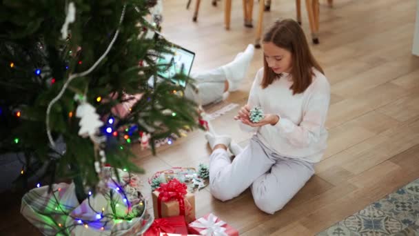Chica Sonriente Sosteniendo Cono Para Árbol Navidad Mientras Está Sentado — Vídeos de Stock