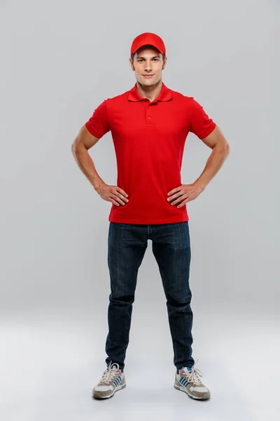 Joven Repartidor Con Uniforme Posando Mirando Cámara Aislada Sobre Pared — Foto de Stock