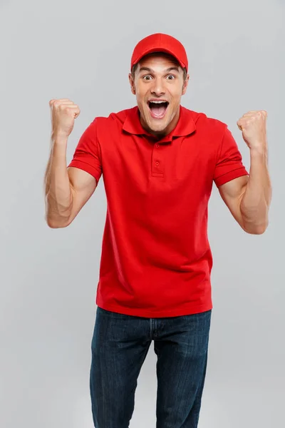 Young Delivery Man Wearing Uniform Screaming While Making Winner Gesture — Stock Photo, Image