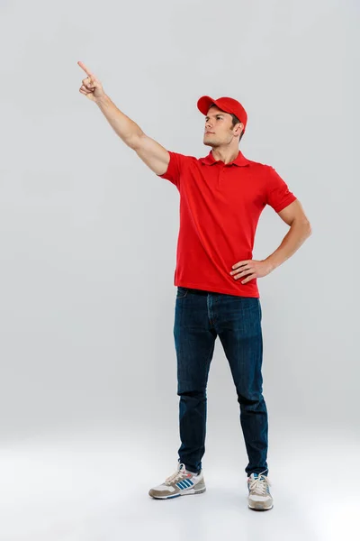 Jovem Entrega Homem Vestindo Uniforme Olhando Apontando Dedo Lado Isolado — Fotografia de Stock