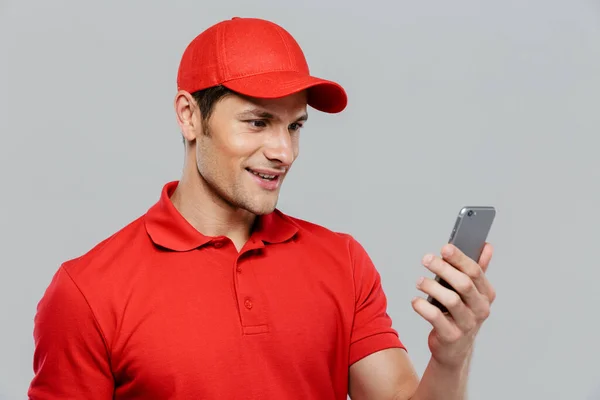 Jovem Homem Entrega Vestindo Uniforme Sorrindo Usar Celular Isolado Sobre — Fotografia de Stock