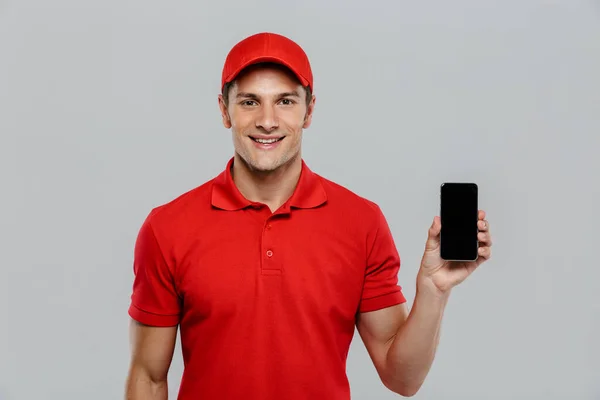 Jovem Entrega Homem Vestindo Uniforme Sorrindo Mostrar Celular Isolado Sobre — Fotografia de Stock