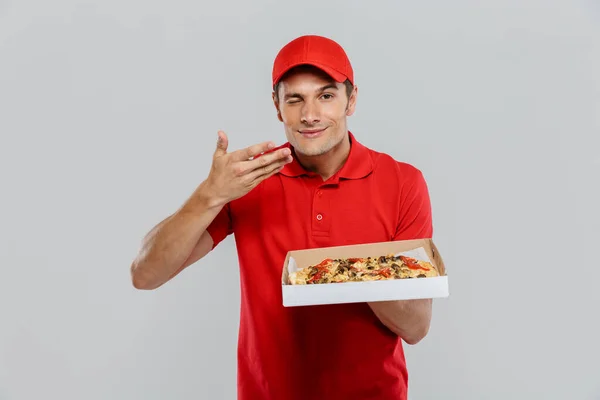 Joven Repartidor Uniforme Oliendo Mientras Muestra Pizza Aislada Sobre Pared — Foto de Stock