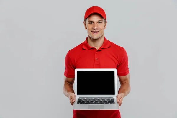 Giovane Uomo Consegna Uniforme Sorridente Mentre Mostra Laptop Isolato Parete — Foto Stock