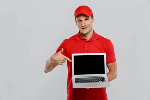 Jonge Bezorger Uniform Toont Wijst Naar Laptop Geïsoleerd Witte Muur — Stockfoto