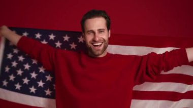 Kırmızı stüdyoda Amerikan bayrağı sallayan mutlu adam.