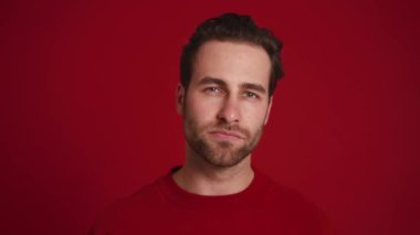 Kırmızı stüdyodaki kamerada eriyen yakışıklı adamın yakın çekim görüntüsü.