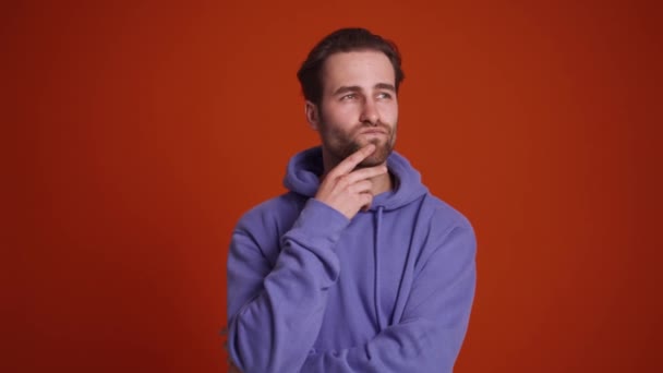 站在橙色工作室里的穿着紫色帽衫的多愁善感的男人 — 图库视频影像