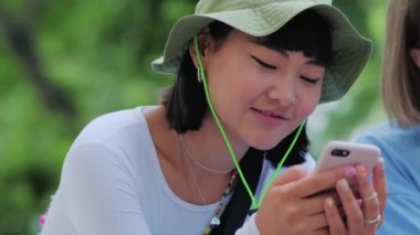 İki gülümseyen çok uluslu seyahat arkadaşı caddedeki telefonlara bakıyor.